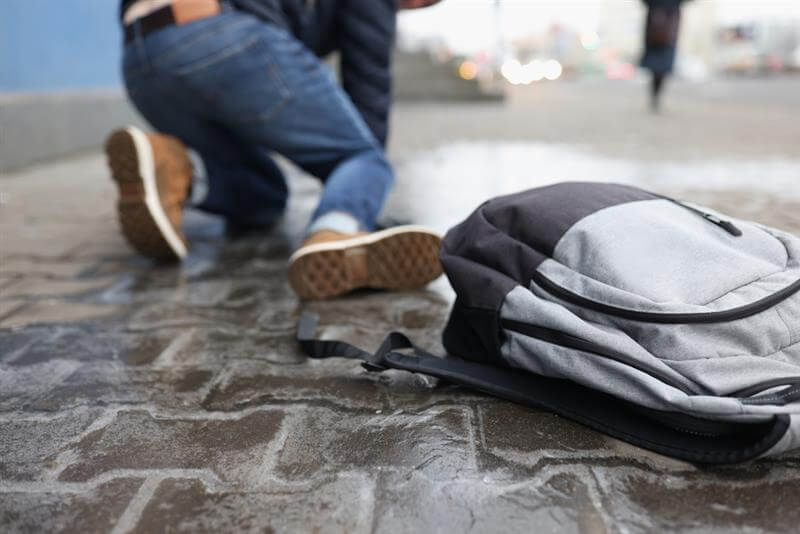Man with backpack felling on slippery sidewalk in winter closeup.