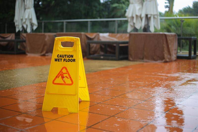 Caution wet floor yellow sign warning while it raining outside.