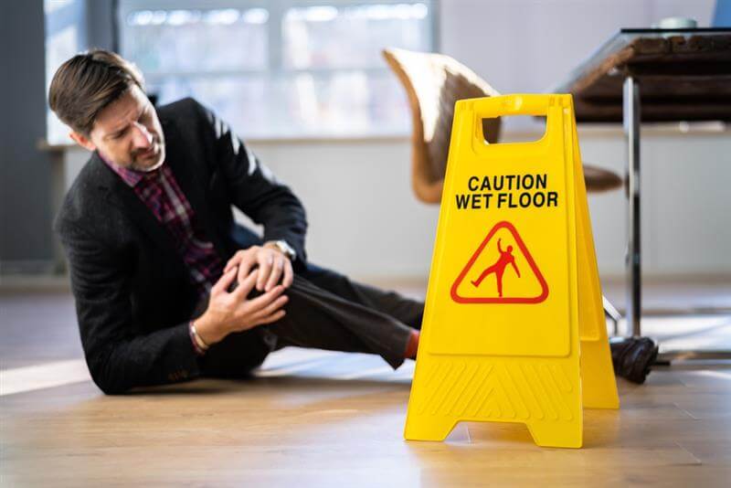 Businessman slip from wet floor suffering injury.